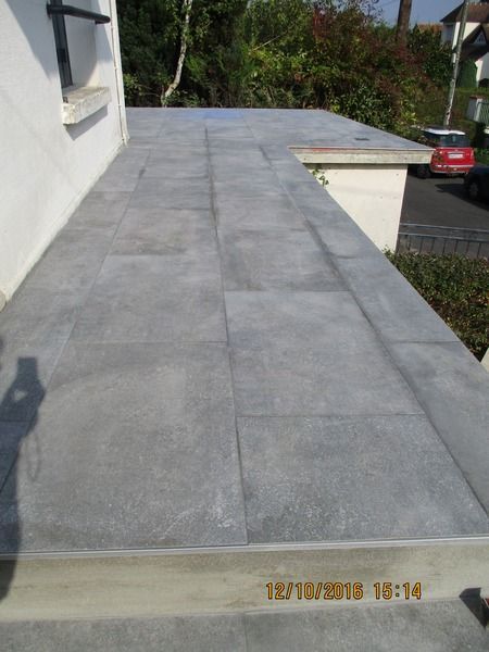 Terrasse surélevée carrelage gris.
