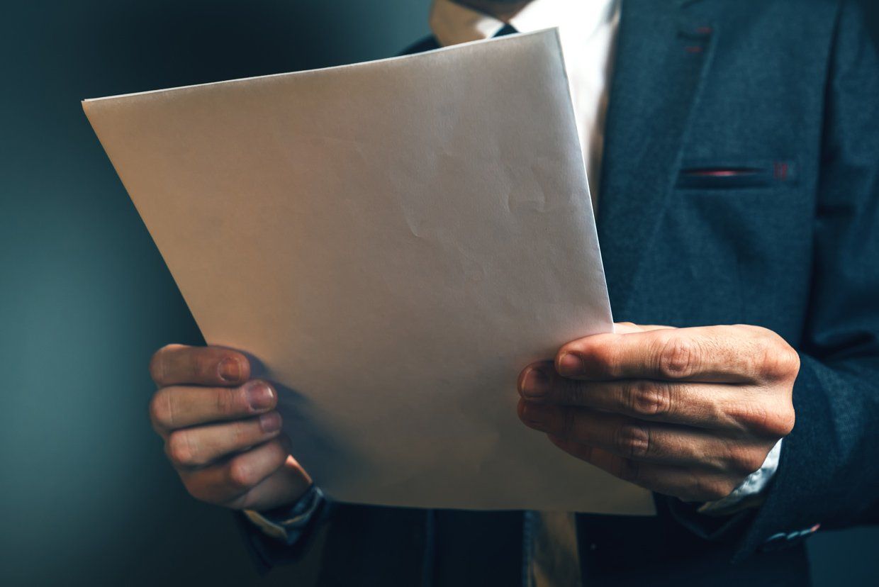 Avocat en costume tenant des documents qu'il lit
