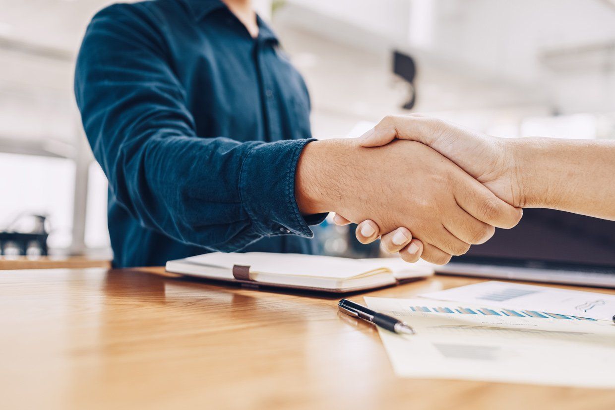 2 personnes se serrant la main sur un bureau