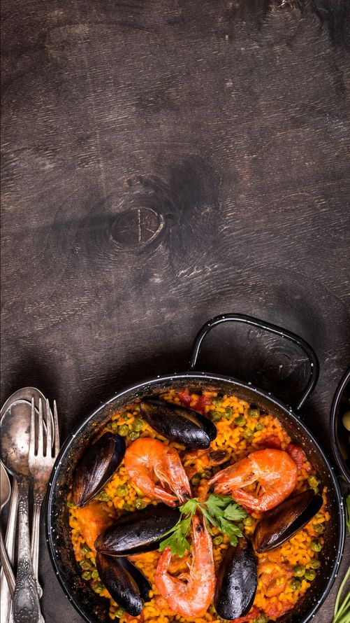 Paella aux crevettes et aux moules dans un poêlon sur une table noir