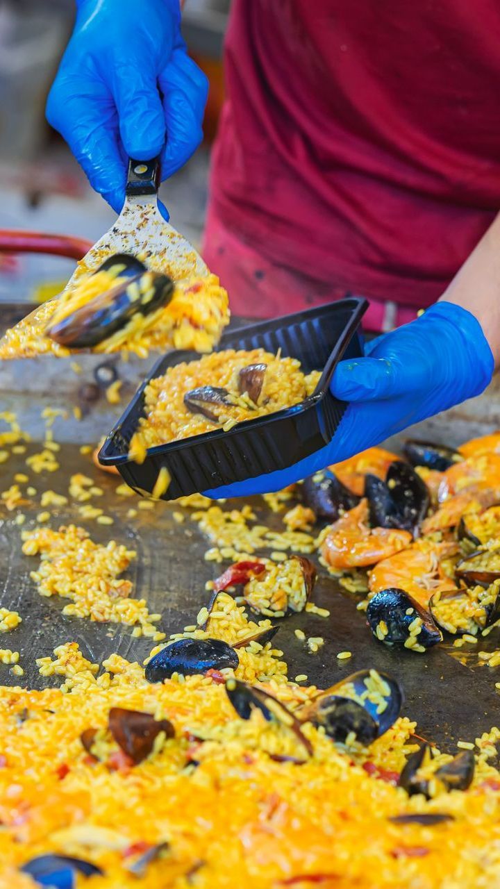 Personne qui met de la paella dans des barquettes de portion individuelle