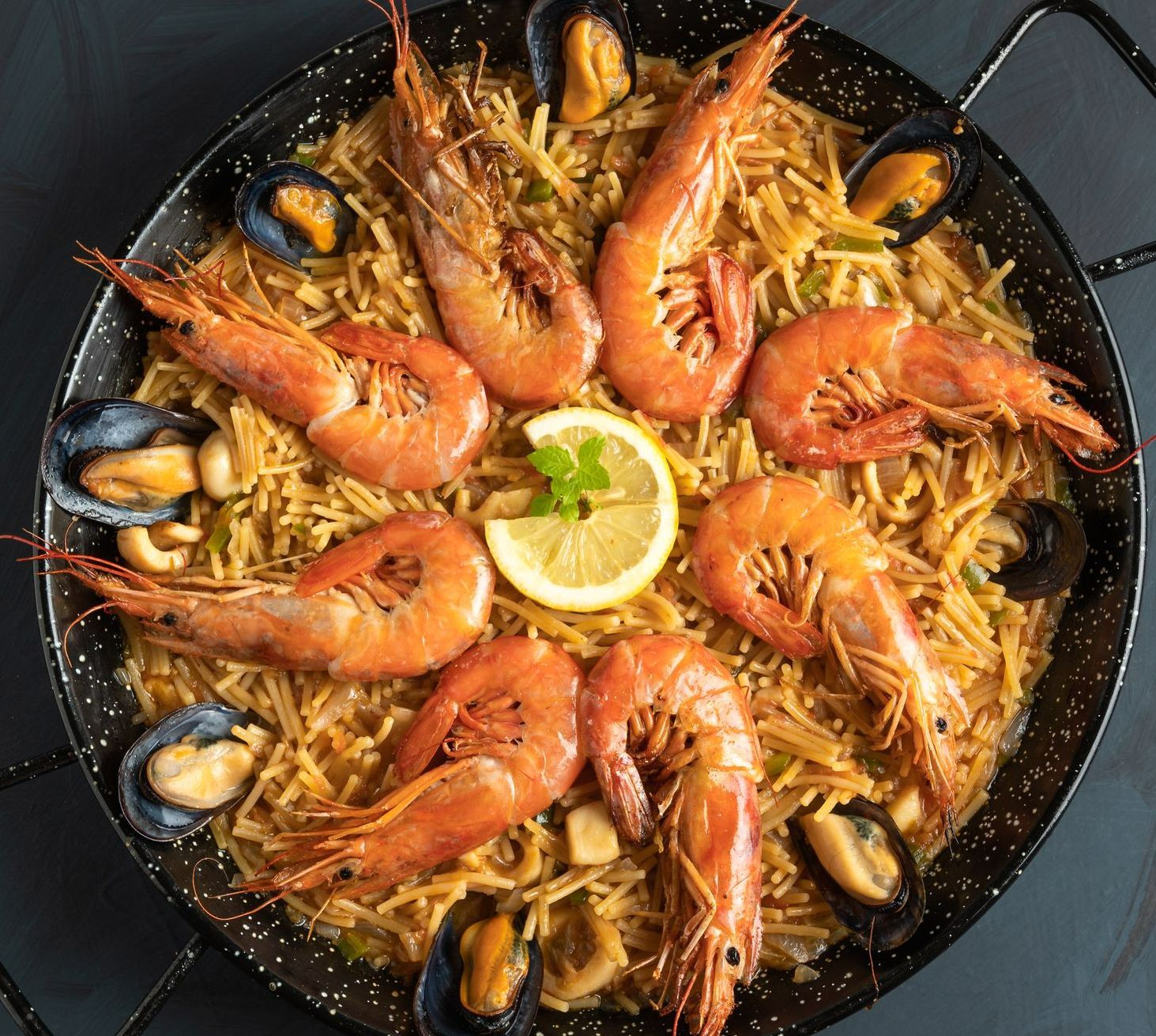 Paella aux fruits de mer avec des moules et des crevettes et une tranche de citron sur le dessus