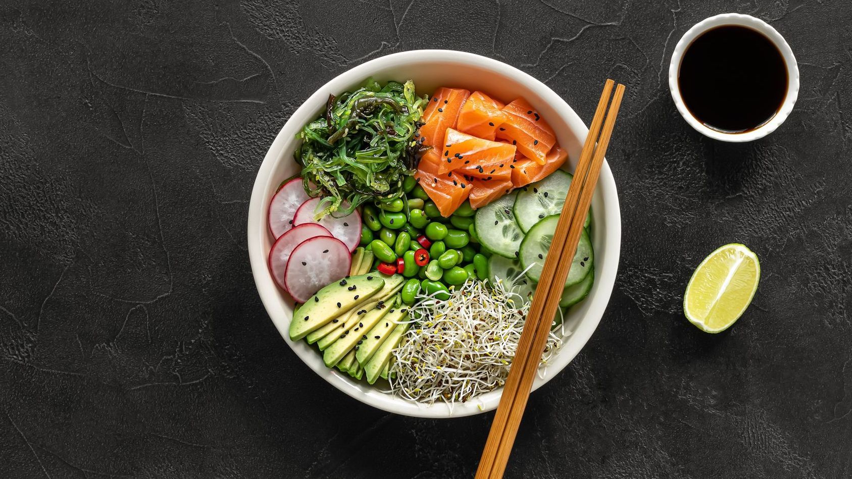 Poke bowl sur une table avec des baguettes et un pot de sauce soja