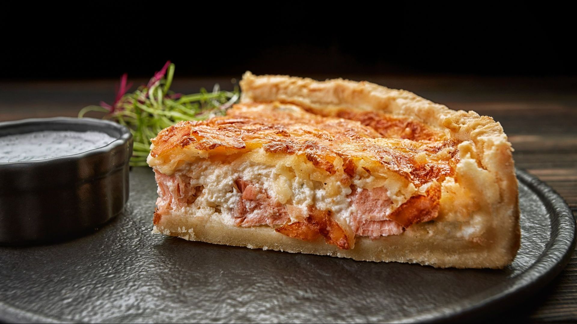 Tranche de quiche au saumon et au fromage sur un plat noir