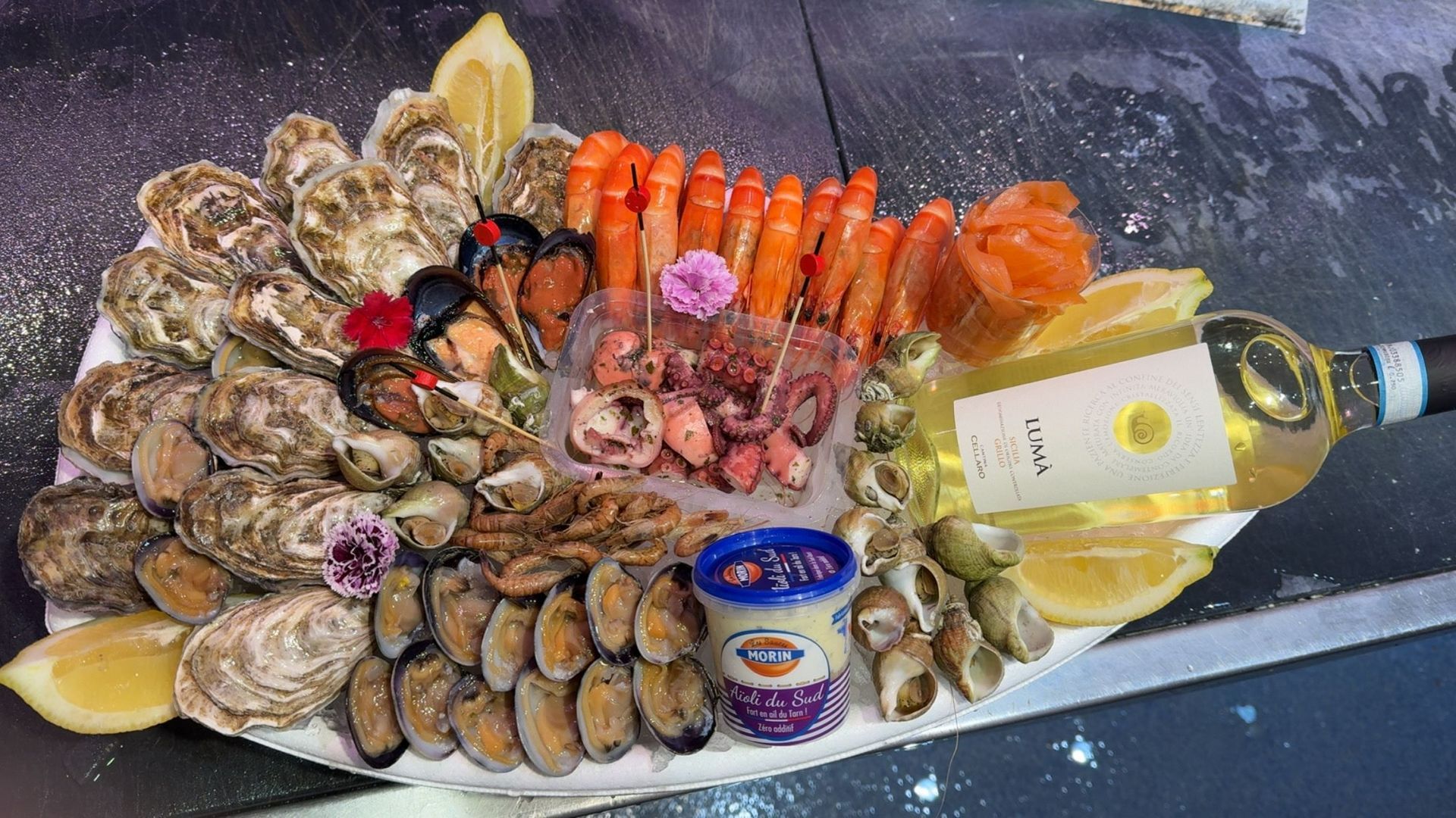Plateau de fruits de mer composé de coquillages et crustacés, d'une bouteille de vin et d'un pot de sauce