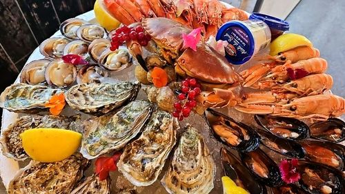 Plateau de fruits de mer composé de crevettes, huîtres, moules, un crabe ainsi que des tranches de citrons et un pot de sauce
