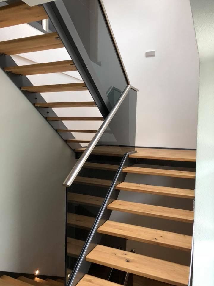 Holztreppe mit dunklem Glasgeländer