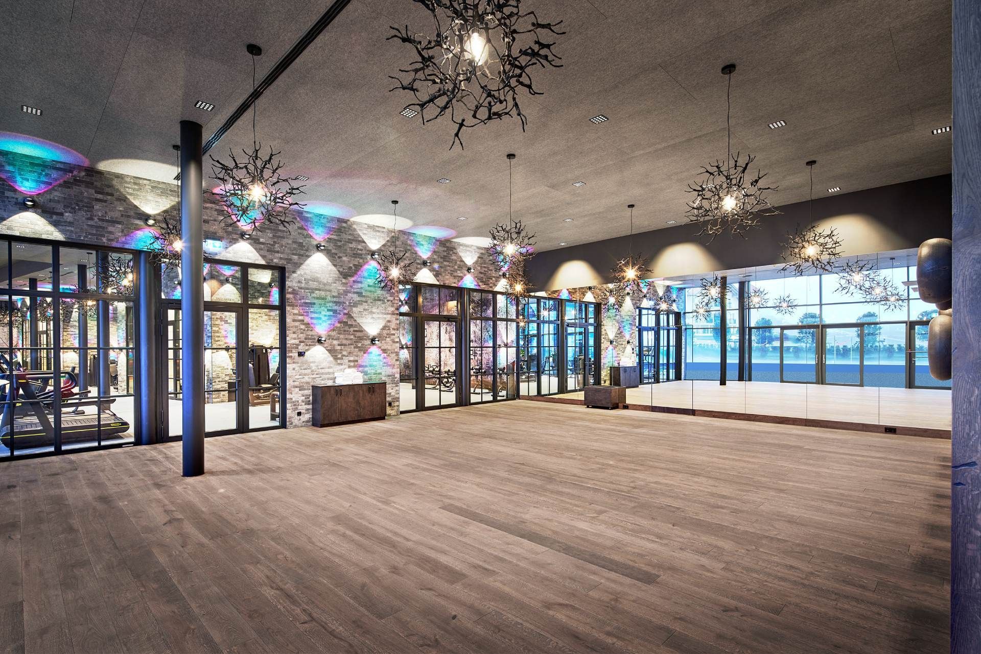 großer Trainingsraum eines Fitnessstudios mit Spiegelfront