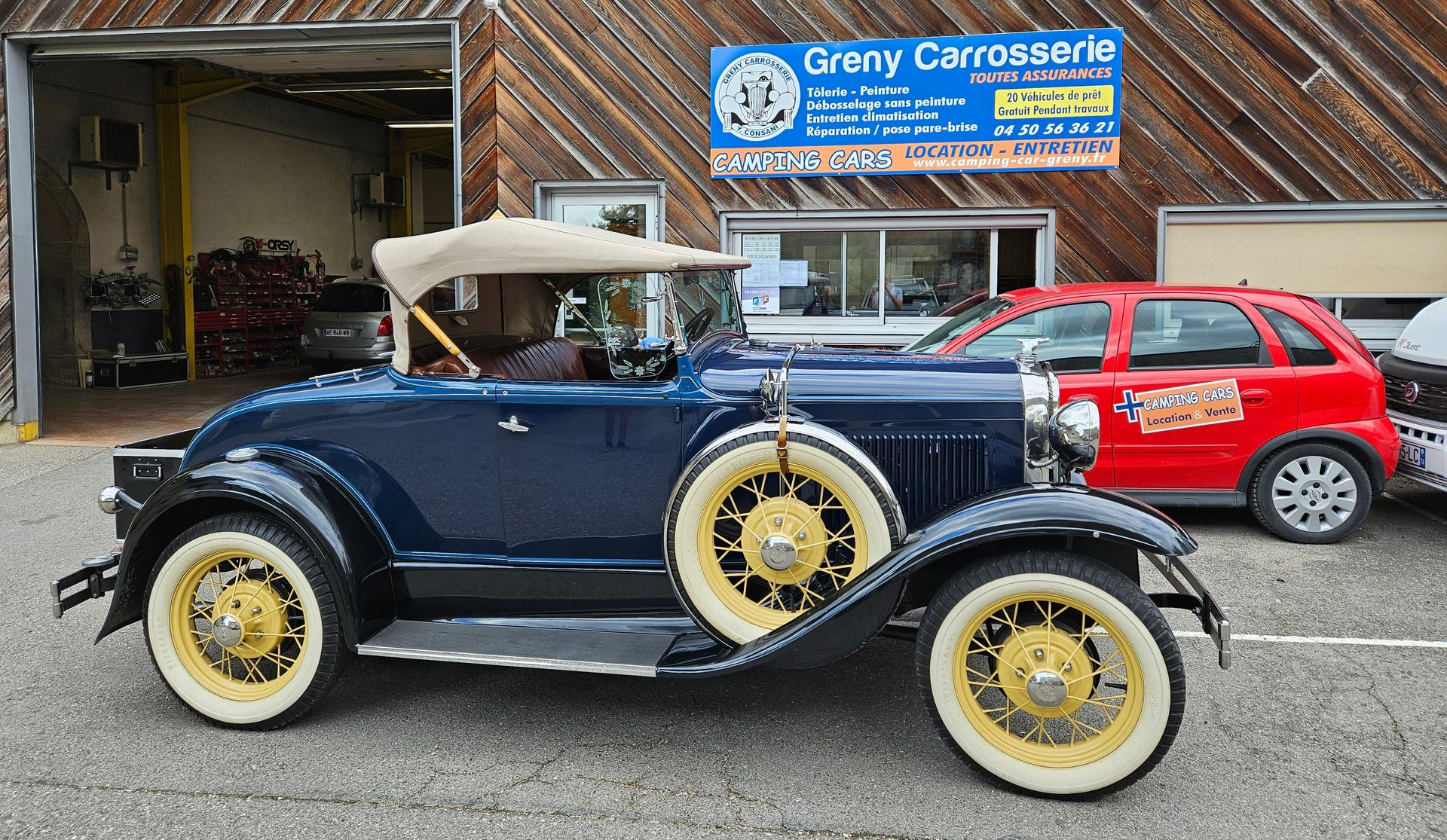 Cabriolet vintage bleu foncé garé devant un atelier de réparation automobile