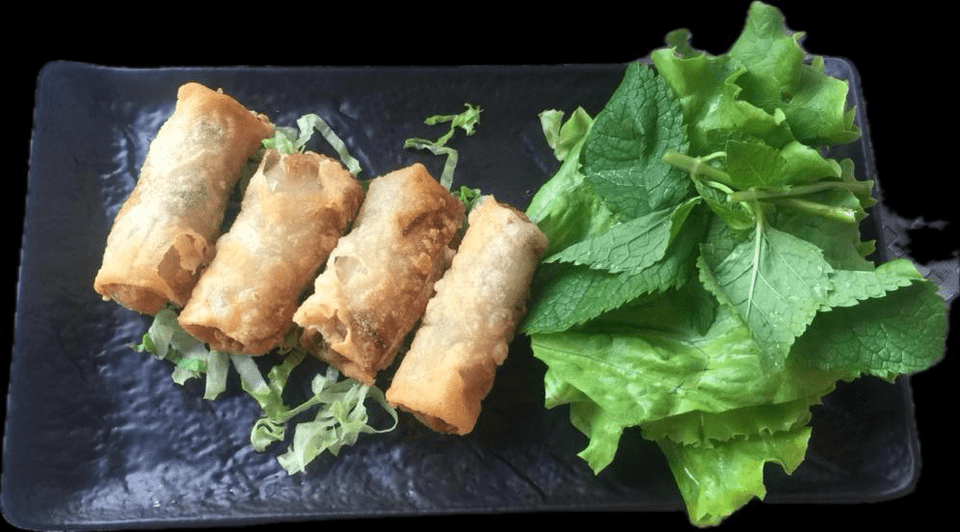 Une assiette noire garnie de rouleaux de printemps et de feuilles de laitue.