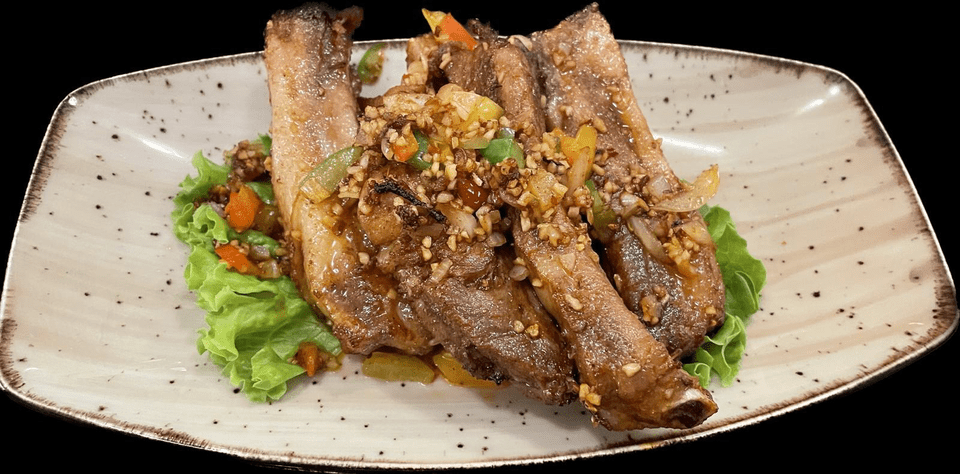 Une assiette blanche garnie de viande et de légumes sur fond noir