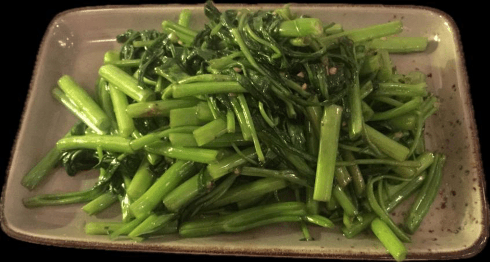 Une assiette de haricots verts sur fond noir.