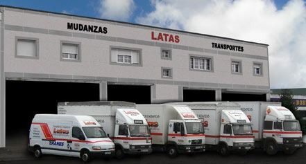 Varios camiones están estacionados frente a un edificio que dice mudanzas
