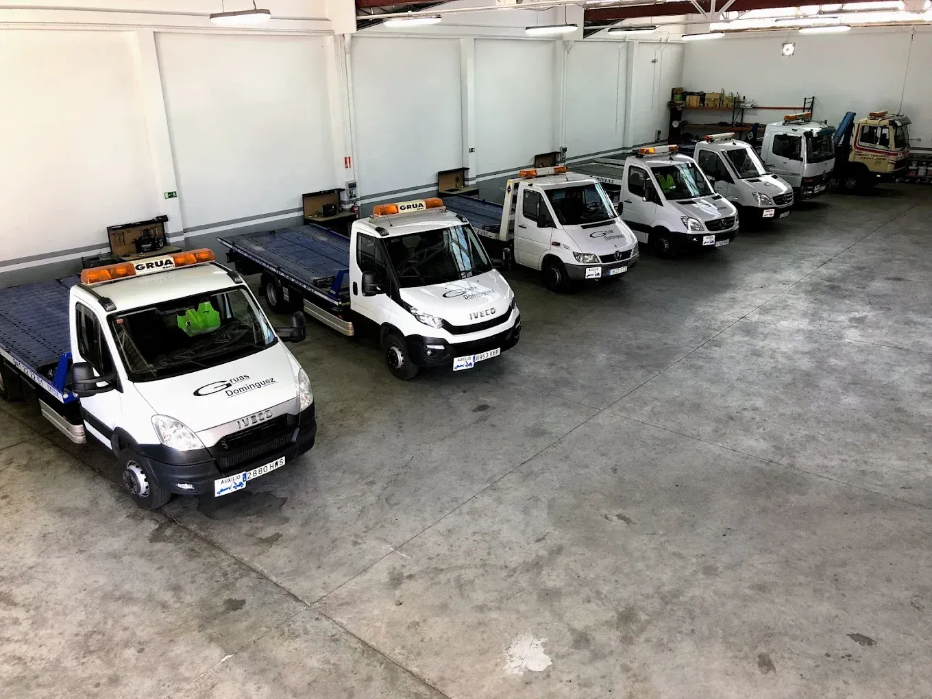 Varias camionetas blancas de servicio estacionadas en el garaje de un almacén, vistas desde arriba.
