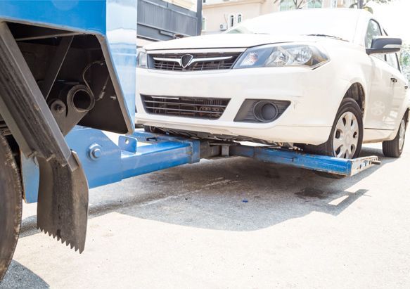 Un coche blanco está siendo remolcado por una grúa.