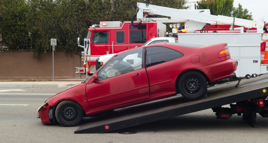 Un coche rojo está siendo remolcado por una grúa.
