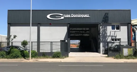 Entrada principal de un edificio Dominguez con puerta negra y fachada blanca a lo largo de una calle