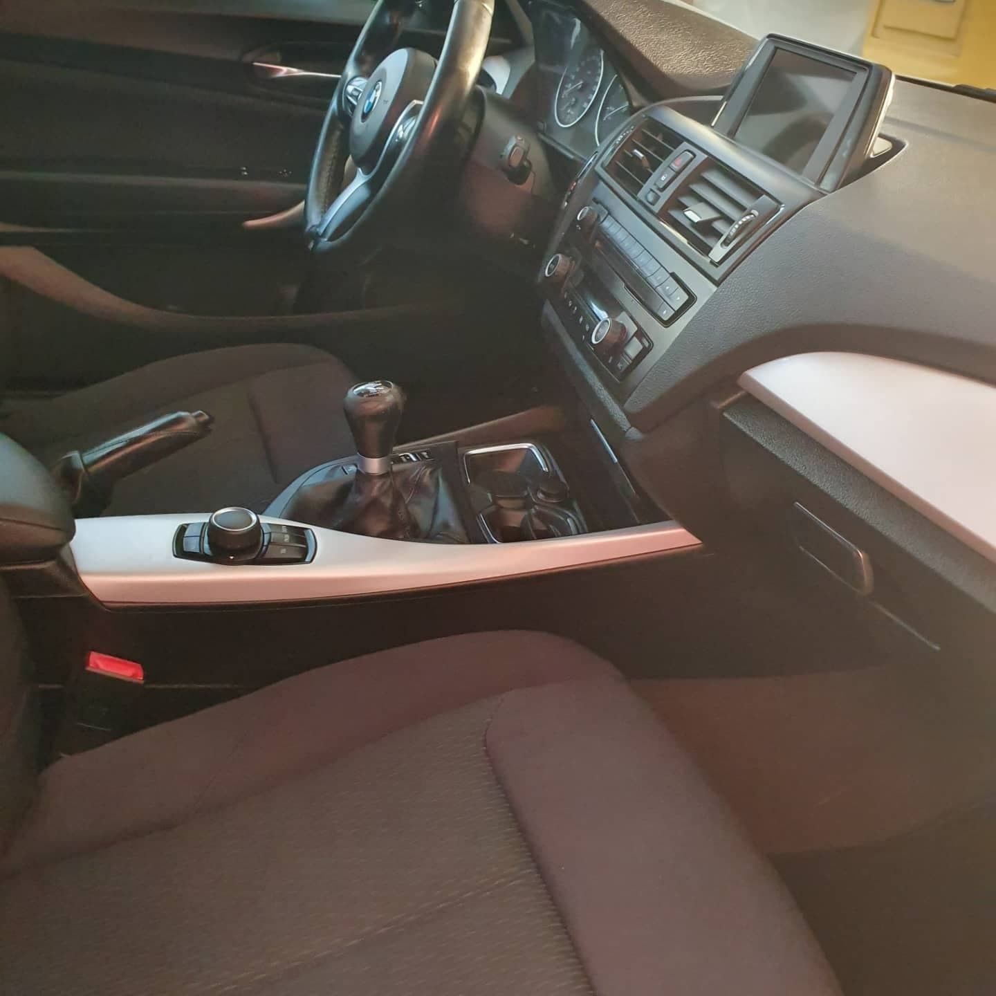 Interior del coche con asientos negros, volante, consola central y palanca de cambios a la vista.