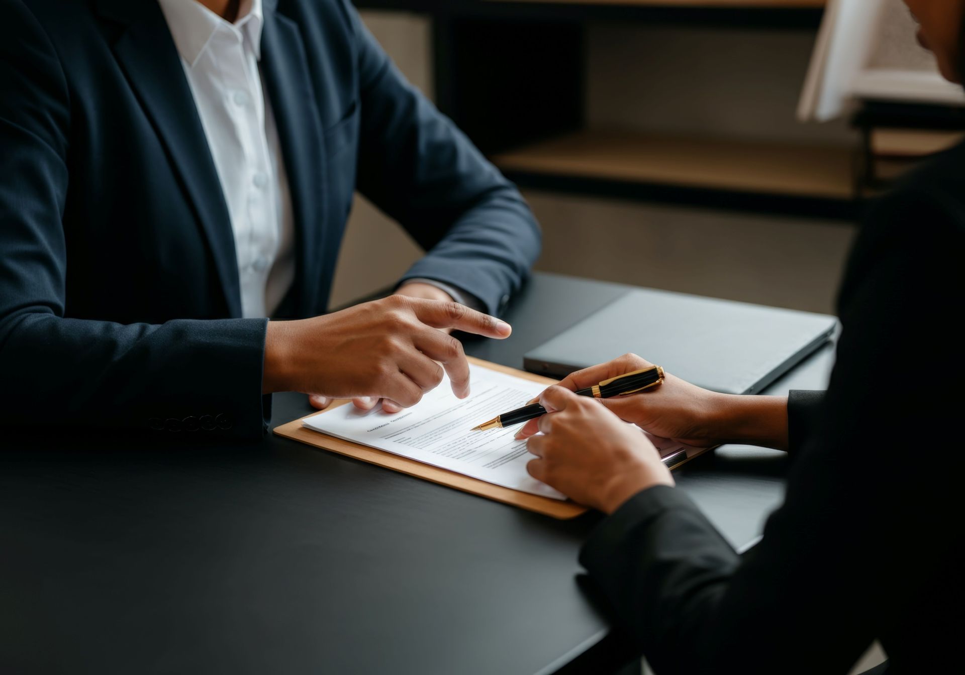 Deux personnes examinant un document à un bureau, l’une tenant un stylo lors d’une réunion professionnelle