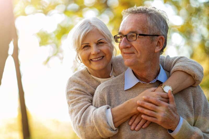 Un couple âgé souriant en plein air sous le soleil chaud,