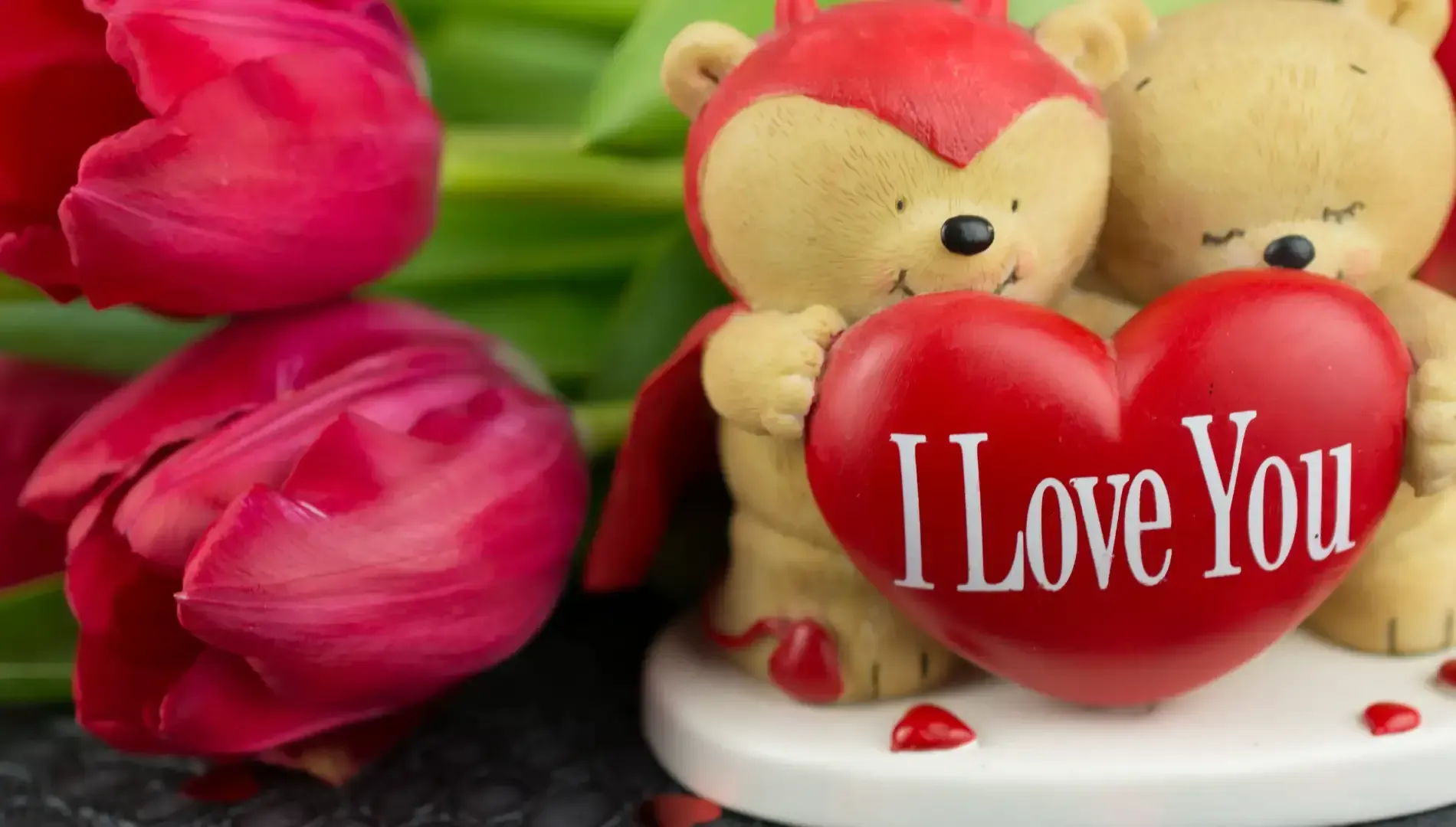 Dos ositos de peluche sosteniendo un corazón rojo con 