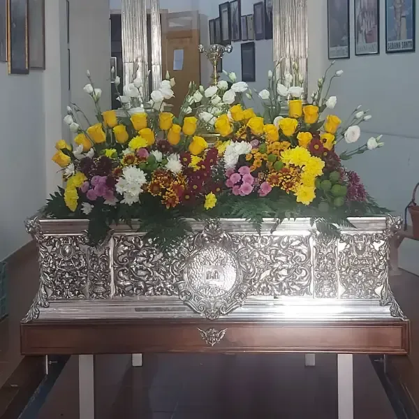 Mujer sosteniendo un ramo y un gran objeto en forma de corazón frente al escaparate de una tienda.