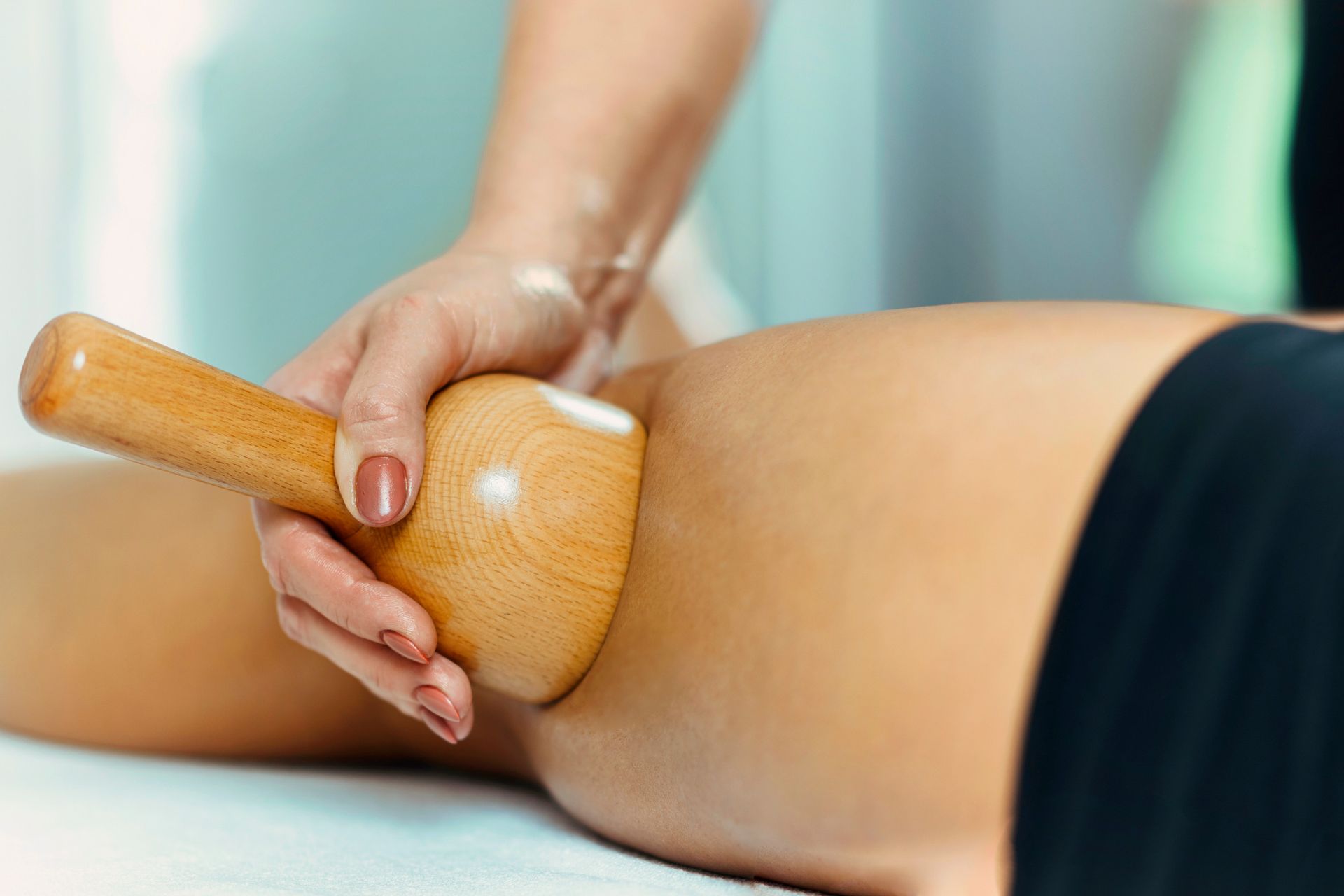 Persona recibiendo un masaje de madera en la pierna en un spa.