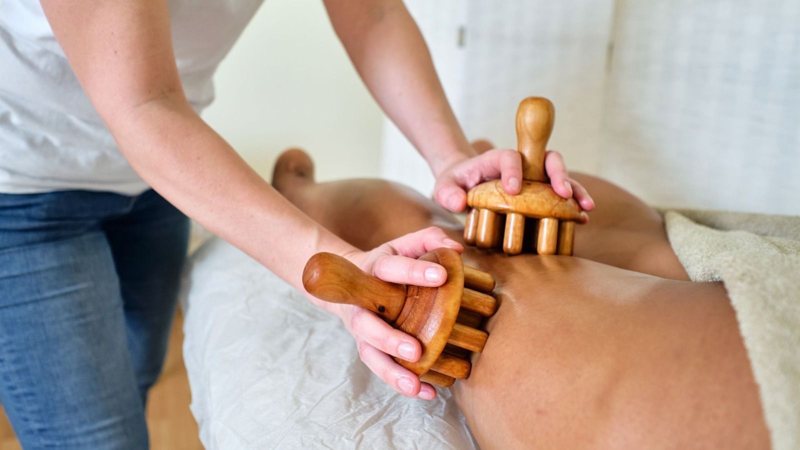 Persona recibiendo un masaje de madera en la espalda en un entorno de spa.