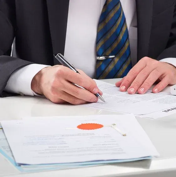 Un hombre con traje y corbata está escribiendo en un trozo de papel.