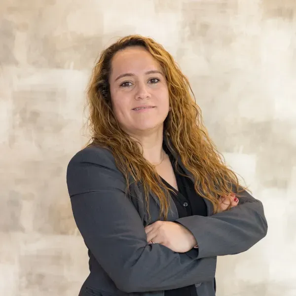 Una mujer con traje posa para una foto con los brazos cruzados.