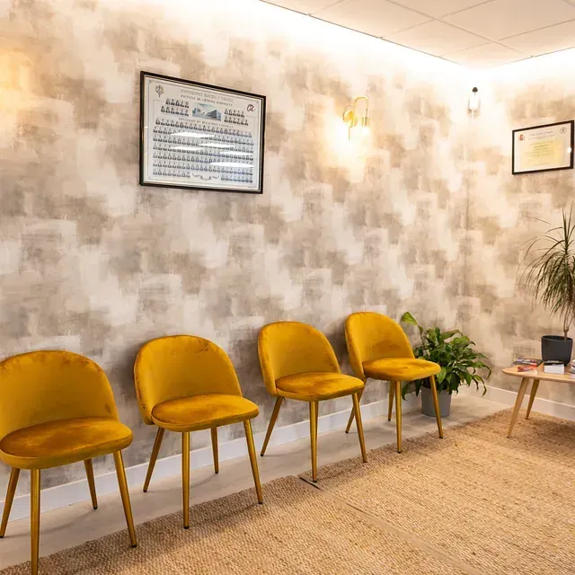 Una fila de sillas amarillas están alineadas en una sala de espera.