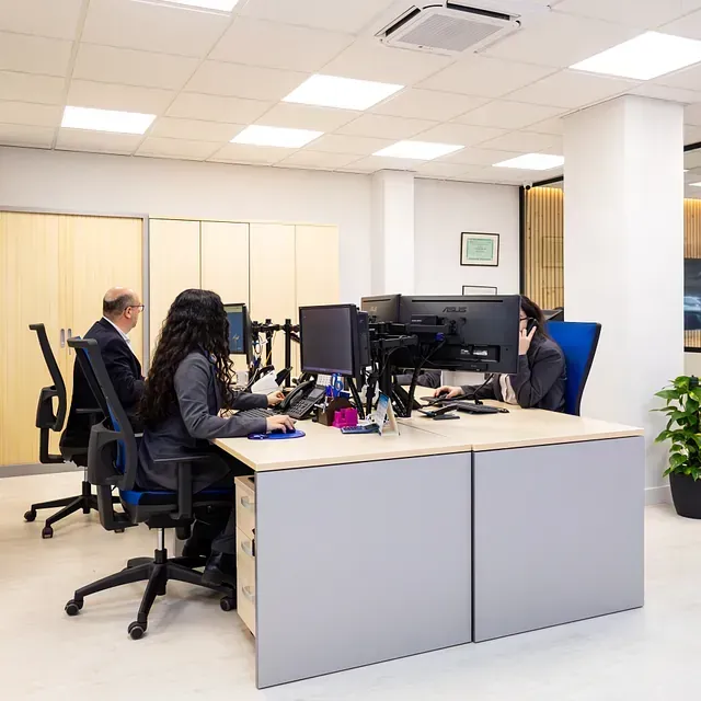 Un grupo de personas están sentadas en escritorios en una oficina trabajando con computadoras.