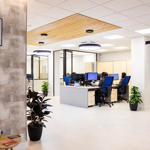 Un grupo de personas están sentadas en escritorios en una oficina.