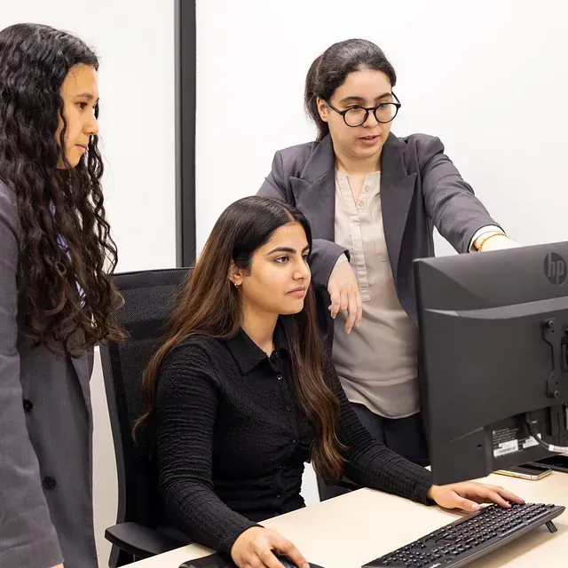 Tres mujeres miran un monitor de computadora HP