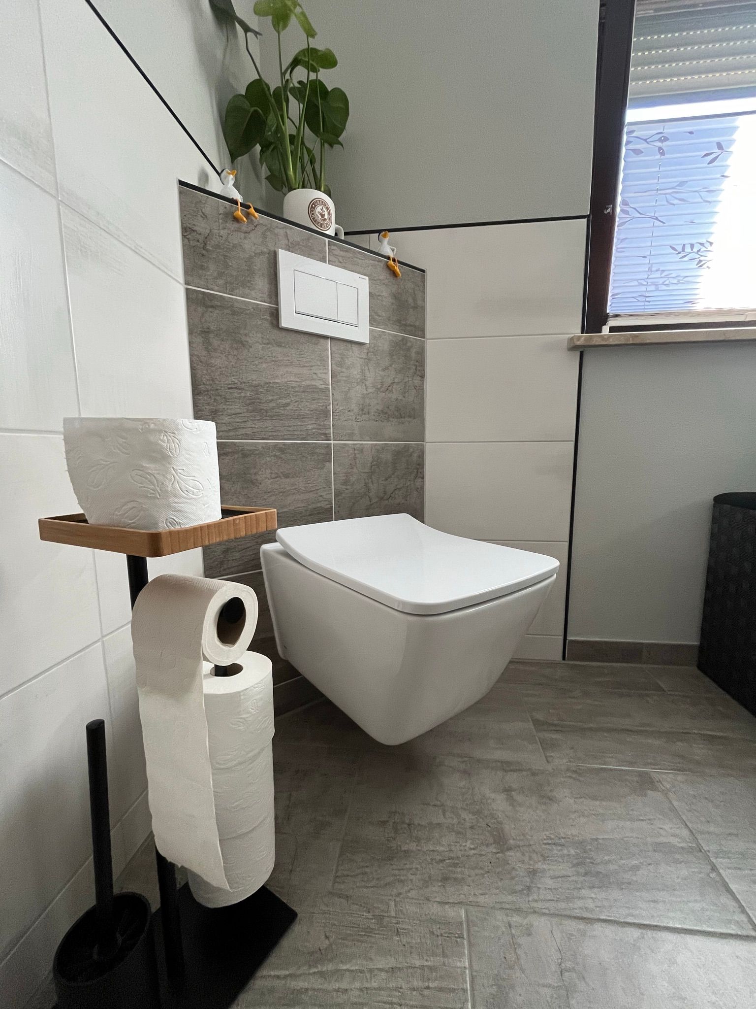 Ein Badezimmer mit Toilette, Papierhandtüchern und Fenster.