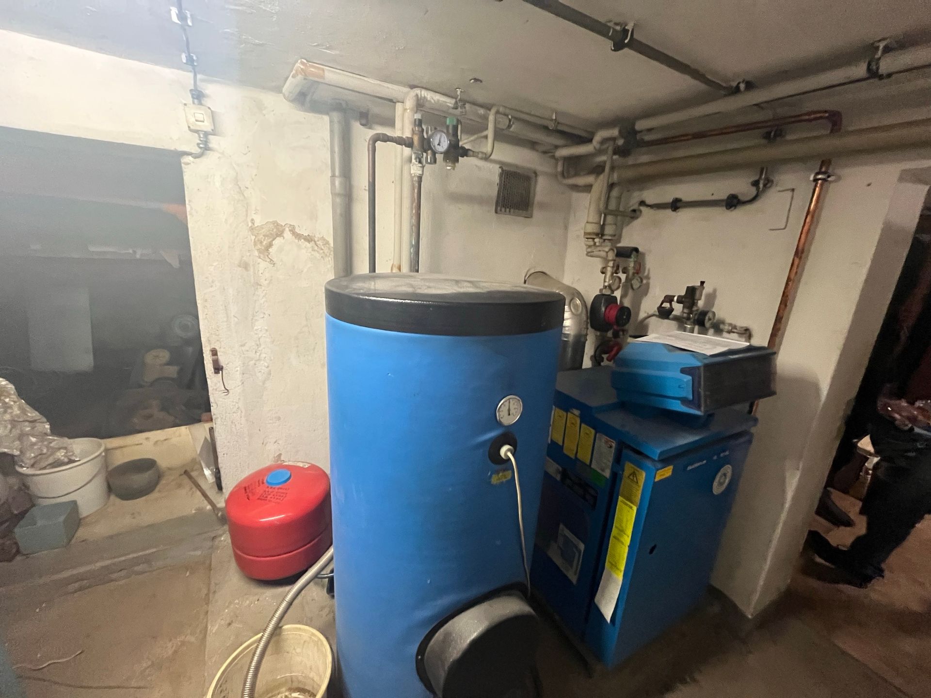 Ein blauer Heizkessel steht in einem Raum neben einer weißen Wand.