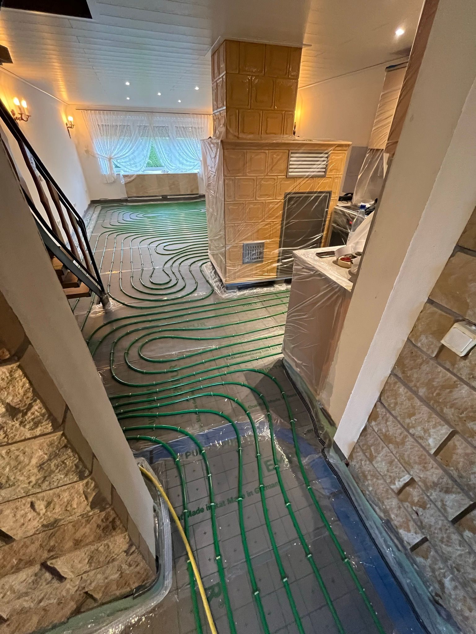 Ein Raum mit Kamin und Treppe und einem grünen Rohr auf dem Boden.