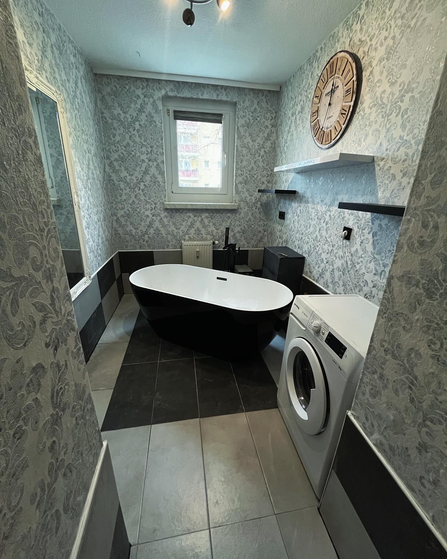 Ein Badezimmer mit Badewanne, Waschmaschine und Trockner und einer Uhr an der Wand.