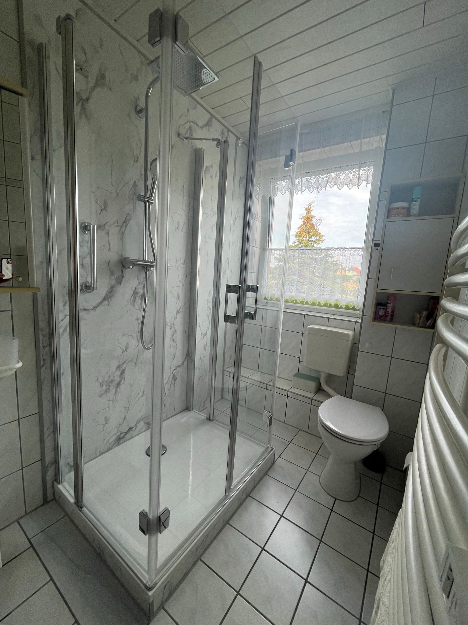 Ein Badezimmer mit Toilette, Dusche und Fenster.