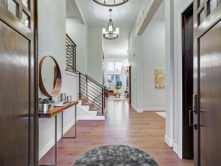 Un pasillo de una casa con una alfombra y un espejo.