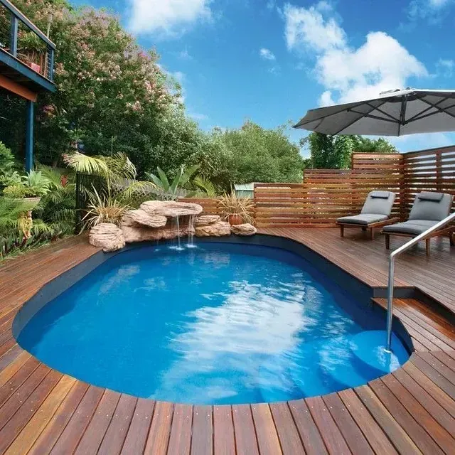 Una gran piscina está rodeada por una terraza de madera.