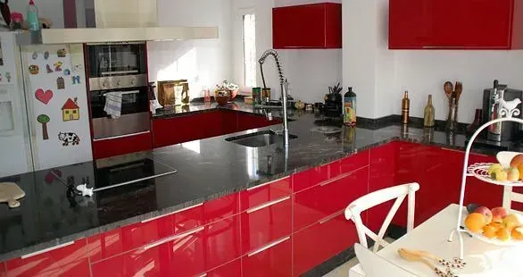 Una cocina con gabinetes rojos y encimeras negras.