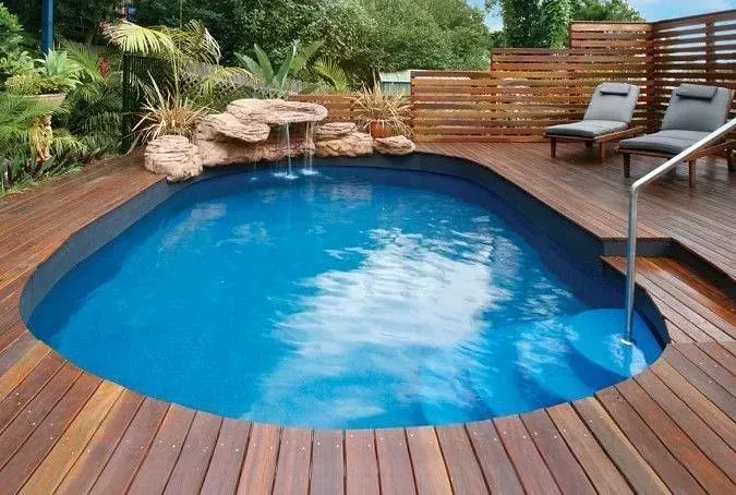 Una pequeña piscina está rodeada por una terraza de madera.
