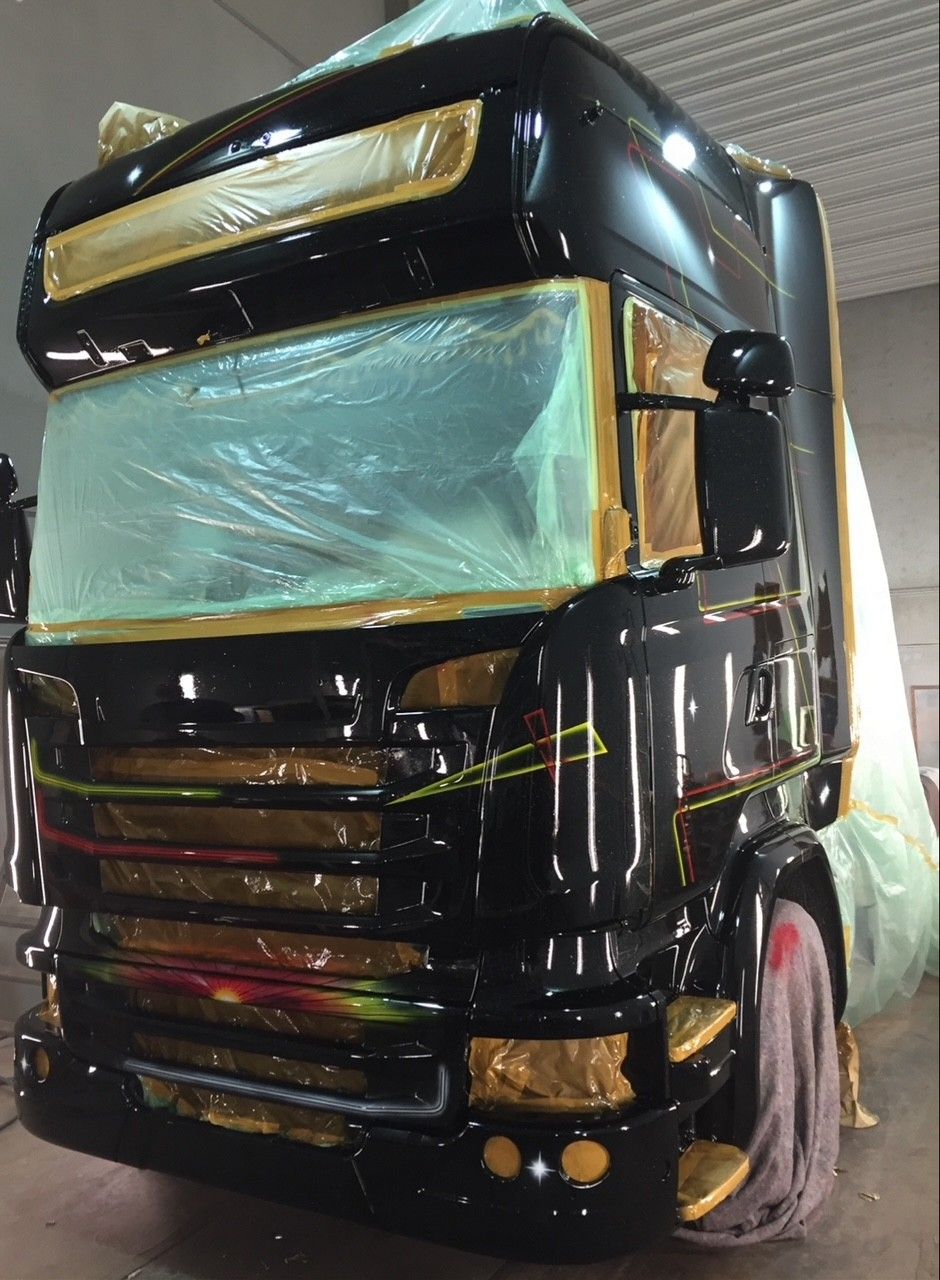 LKW wird neu lackiert in Schwarz mit rot-gelben geometrischen Mustern