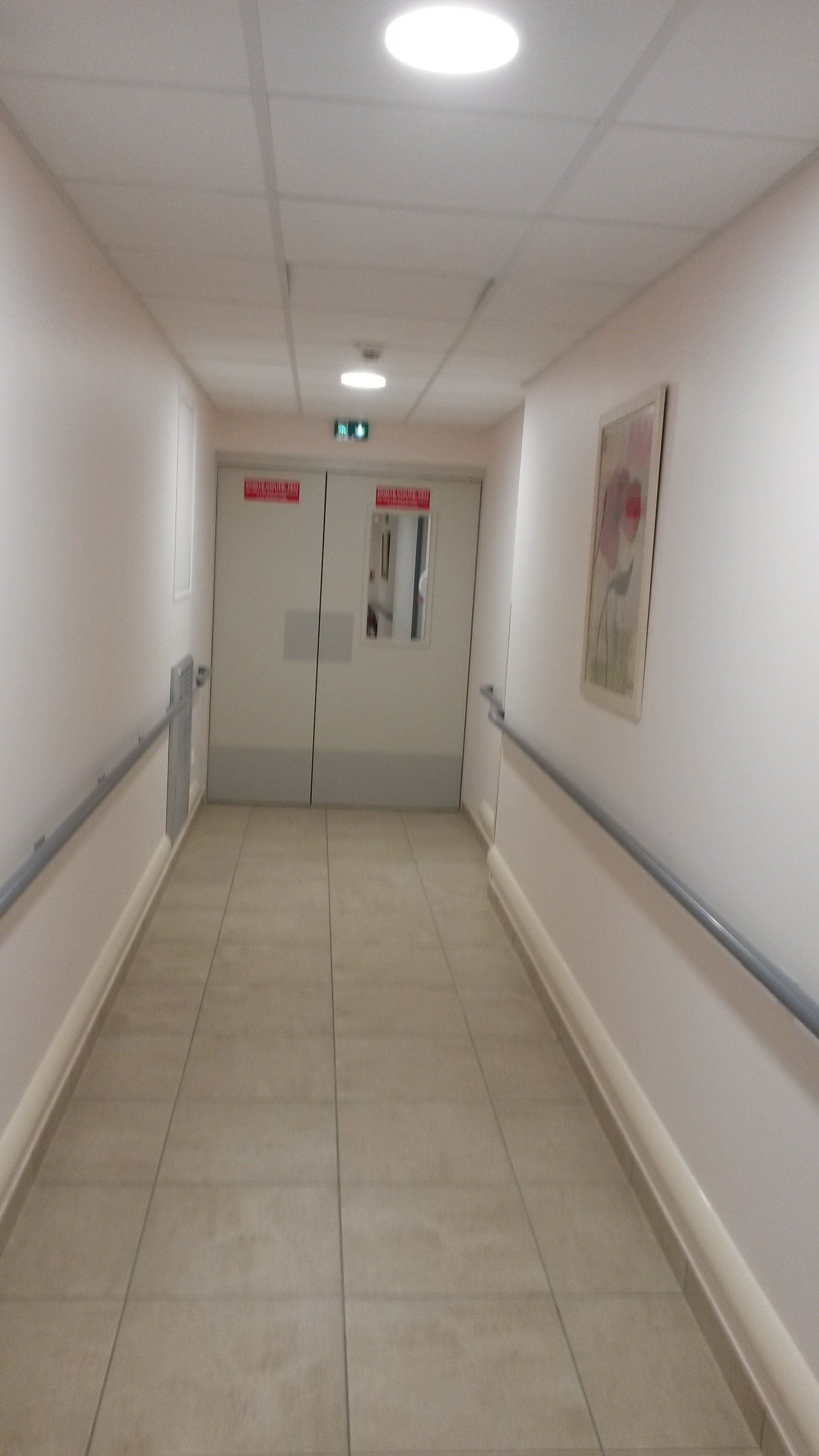 Mains courantes dans un couloir avec une porte coupe-feu