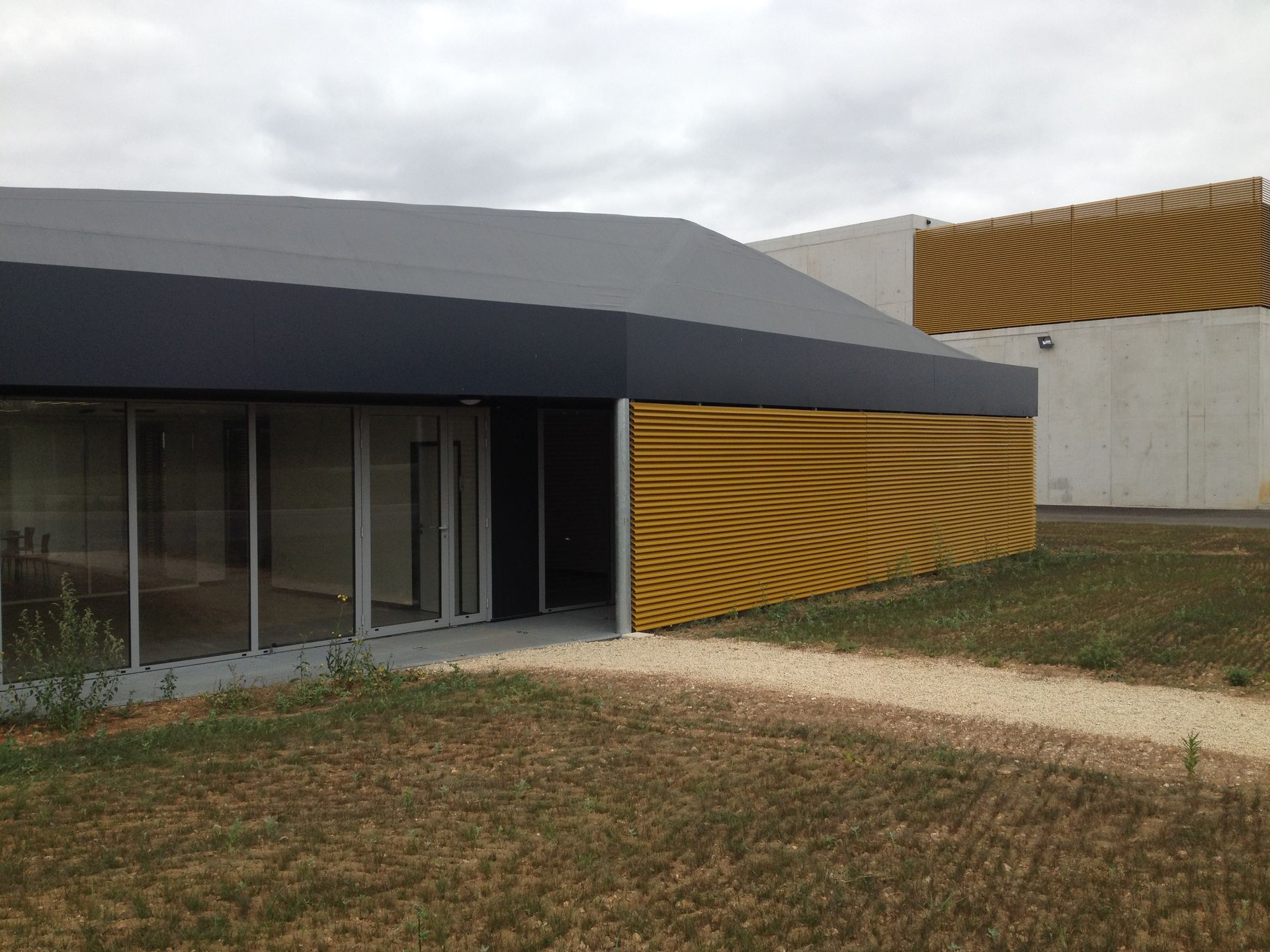 Brise-soleil jaune  sur une entreprise aux murs gris