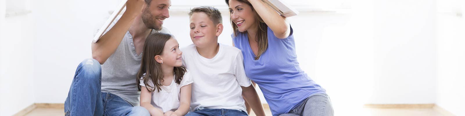 Eine Familie sitzt in ihrem neuen Zuhause auf dem Boden.