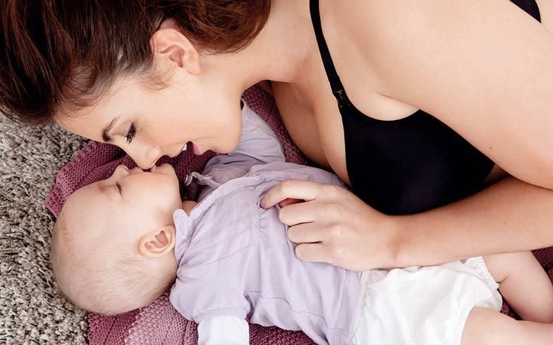 Eine Frau liegt mit einem Baby auf dem Boden.