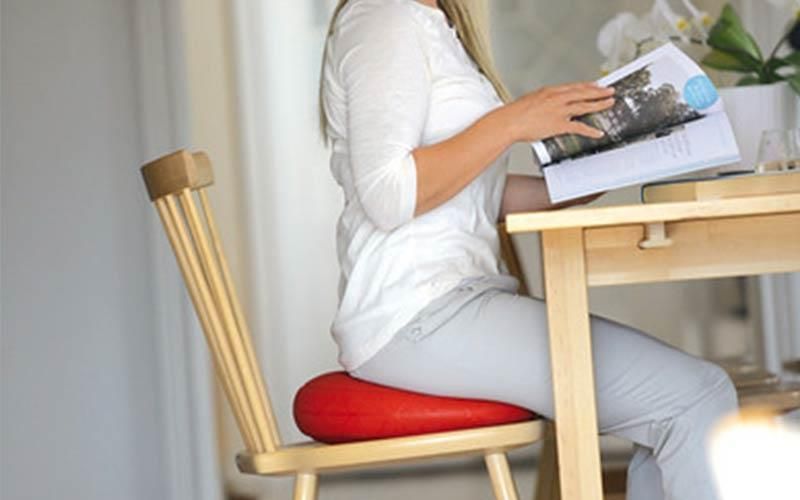 Eine Frau sitzt an einem Tisch und liest eine Zeitschrift.