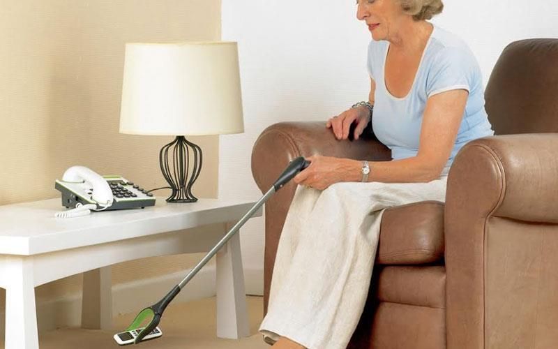 Eine ältere Frau sitzt auf einem Stuhl und hält einen Krallenreiniger in der Hand.